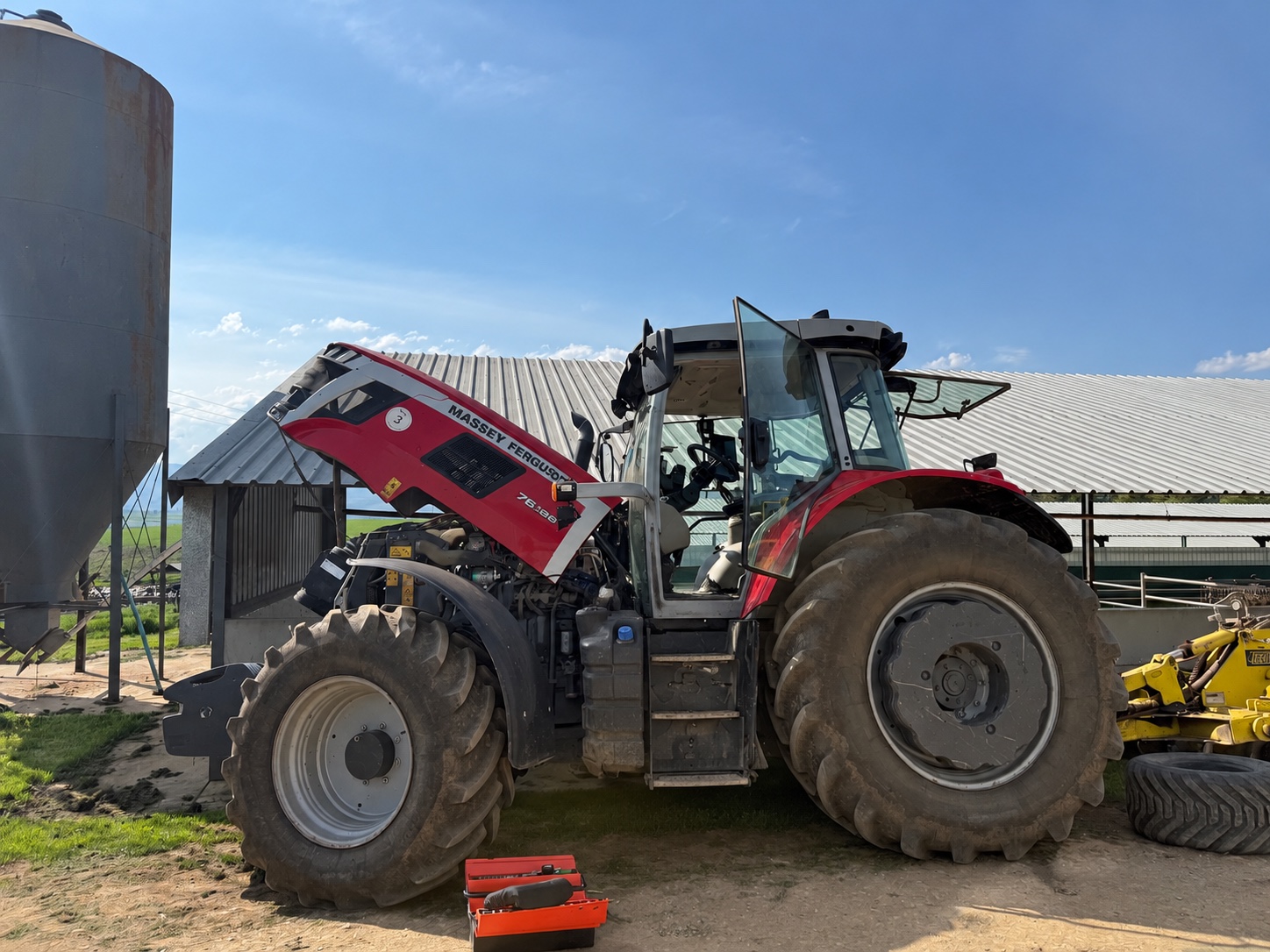 Tractor Massey Ferguson con capó levantado en una granja; fotografía ilustrativa editada