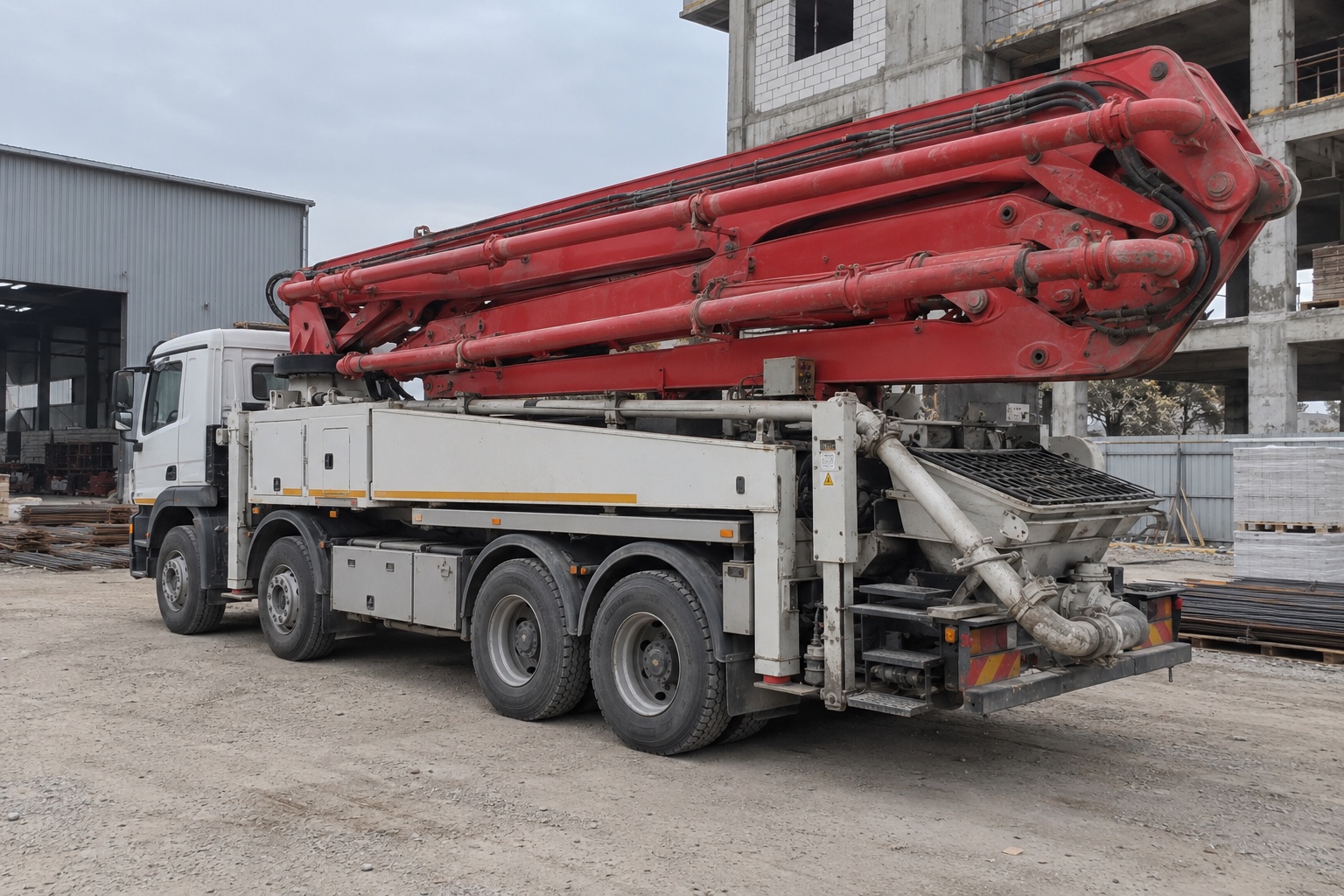 Pompe à béton sur camion avec flèche repliée et stabilisateurs rentrés dans un dépôt de Tachkent — illustration