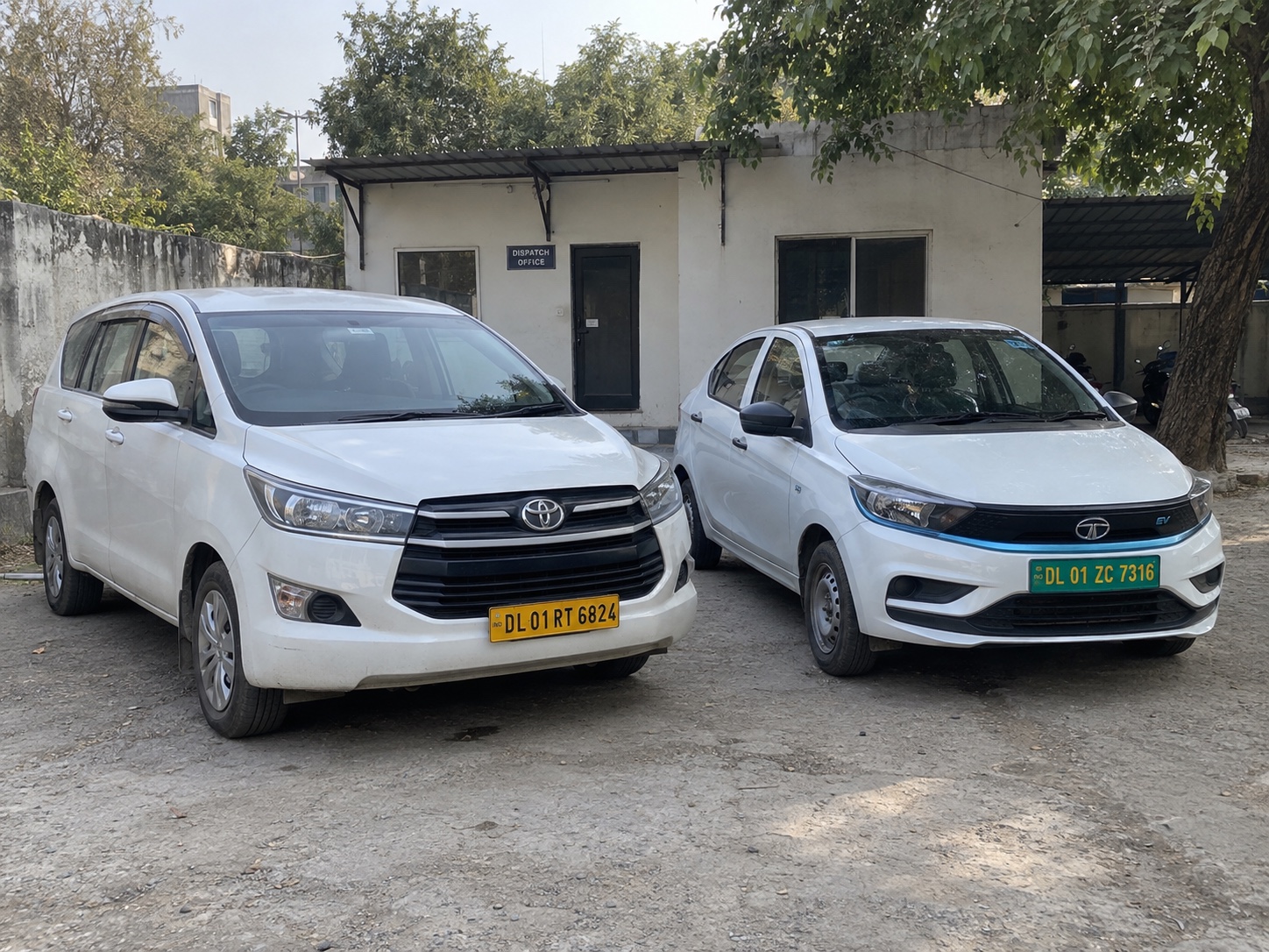 Toyota Innova Crysta and Tata XPRES-T EV transfer vehicles parked at a dispatch yard in Delhi, India