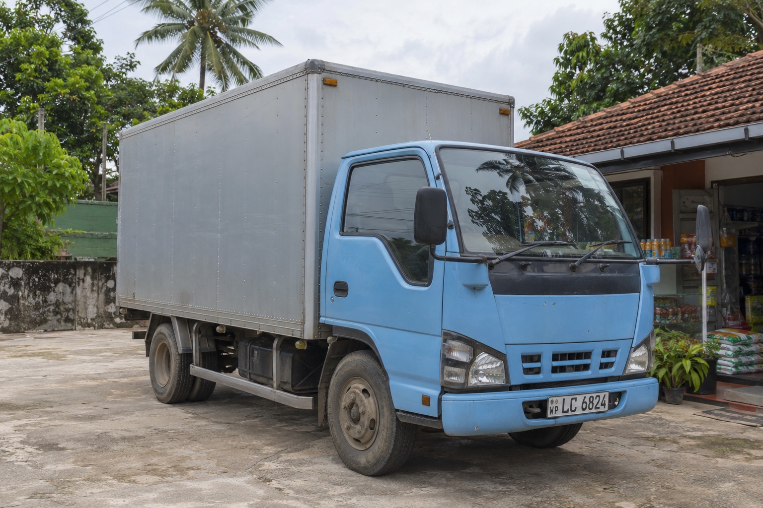 Small food delivery truck at an off-street retail receiving area in Sri Lanka — illustrative scene